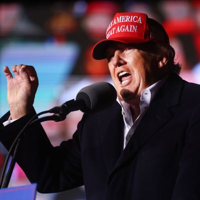 USA:s tidigare president Donald Trump talar i mikrofon på ett kampanjevenemang i Arizona. Han har på sig sin röda keps med texten "Make America great again". 
