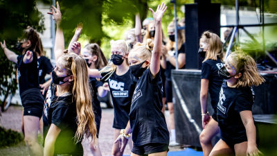 Barn iförda svarta t-skjortor och munskydd dansar.