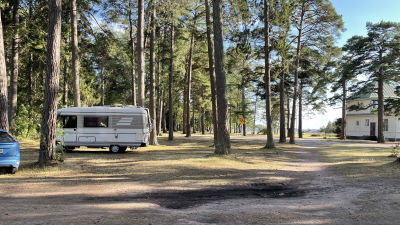 Bild av en husbil som har parkerat mellan träden i Casinoparken i Hangö.