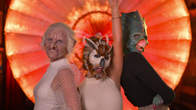 Tre kvinnor i fantastiska djurmasker poserar framför kameran.