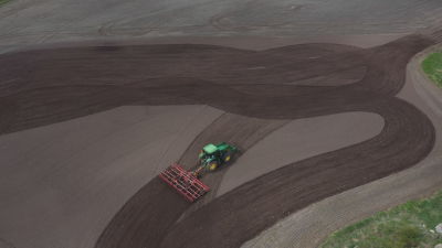 En traktor med harv fotad från luften över en åker