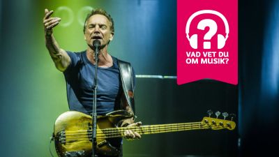 Sting sträcker ut ena armen, har en elbas kring halsen och sjunger i en mikrofon som är i en mikrofonställning.