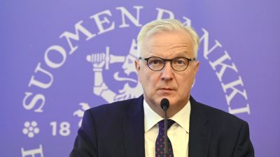 Olli Rehn, chefdirektör för Finlands Bank talar i en mikrofon under en presskonferens.
