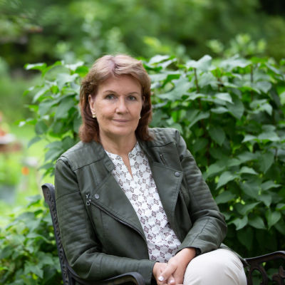 Författare Benita Backas-Andersson sitter i trädgård