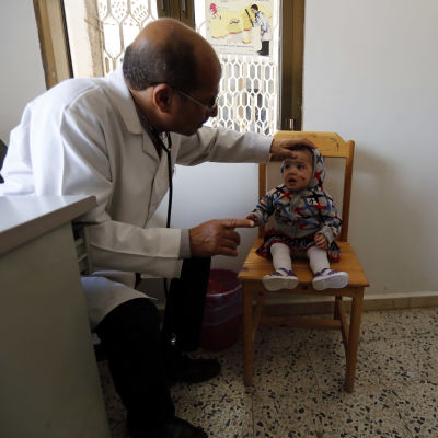 Ett litet barn med ett sår i ansiktet undersöks av en läkare på en mottagning.