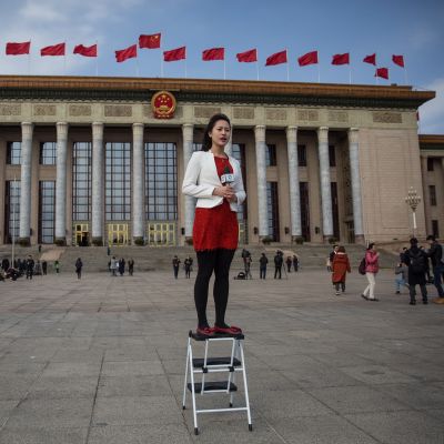 En journalist står på en pall då hon rapporterar utanför Kinas folkongress i Peking
