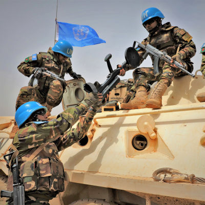 FN:s soldater på ett pansarfordon. En soldat räcker över något till en annan.