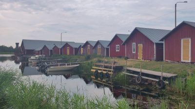 Röda fiskestugor med båtar nedanför som ligger i vattnet.