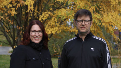 En man och en kvinna fotograferas med gula lövträd i bakgrunden.
