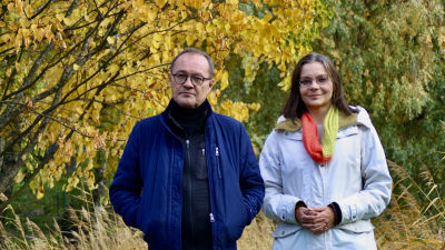 Man och kvinna fotograferade med höstlöv i bakgrunden.