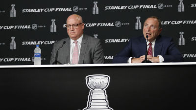Bill Daly i grå kostym och Gary Bettman i mörkblå kostym sitter bakom ett bord på en presskonferens.