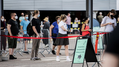 Personer köar utanför mässcentret i Helsingfors för att bli vaccinerade.