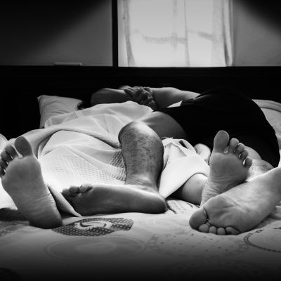 Närbild på fötter tillhörande man och kvinna som ligger i säng
