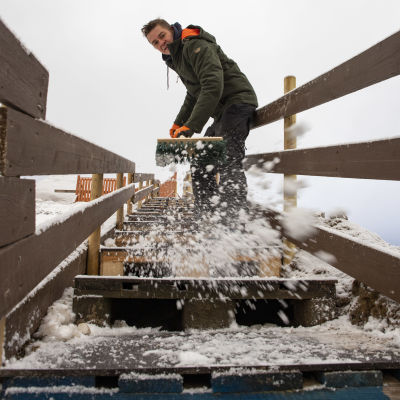 Jarno Rossi lakaisemassa lunta Talvipuiston portailta.