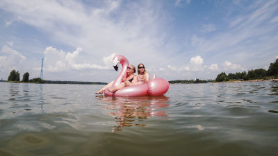 Två människor på en en uppblåsbar flamingo-badring.