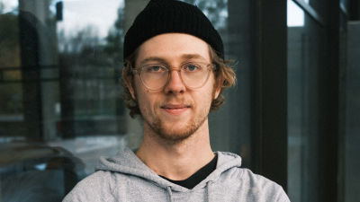 Porträttbild på Jonathan Terlinden, klädd i svart mössa och grå munkjacka.