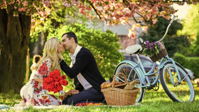 Ett lyckligt par som kysser varandra på en picnik i parken. 