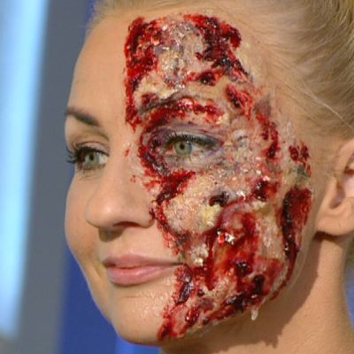 Nainen halloween-maski kasvoillaan.