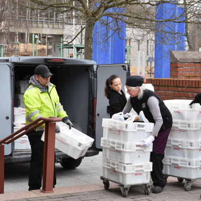 Personer lastar matvaror ur en paketbil. 