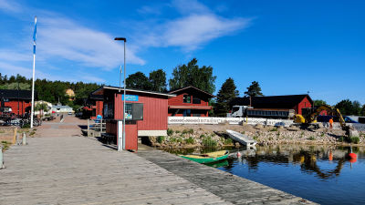 Röda trädhus och träbodar nere vid en strandkant.
