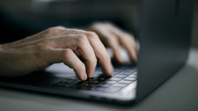 Närbild av händer spm skriver på en dator, laptop.