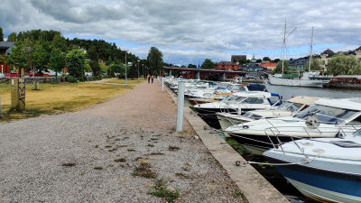 Båtar som gubbar i en å intill en sandväg på land.