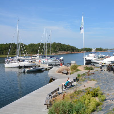 Segelbåtar i Örö gästhamn, och kafégäster i hamnen.