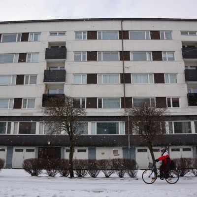 Person cyklar framför höghus en vinterdag i Vasa.