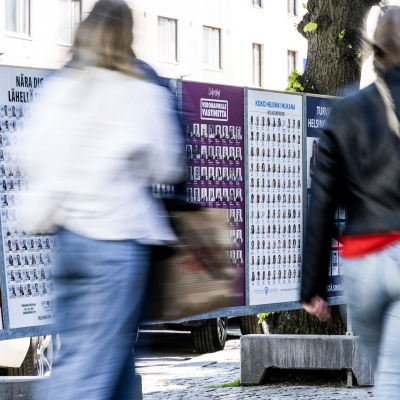 Ihmisiä kävelee kuntavaalimainosten ohi Töölönkadulla Helsingissä.