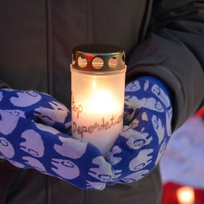 En person håller i ett levande ljus under en demonstration. 