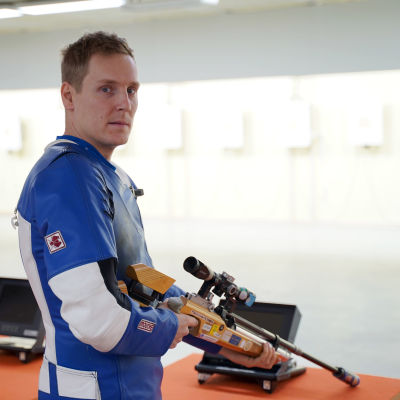 Niklas Hyvärinen står med ett gevär i händerna.