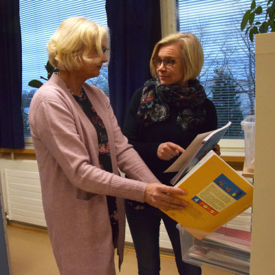 Tua Ljunngren och Susanna Lindholm tittar på skolböcker.