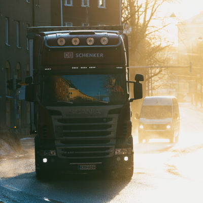 En långtradare kommer körandes i motsljus längsmed en blöt och snöig gata i Helsingfors. 