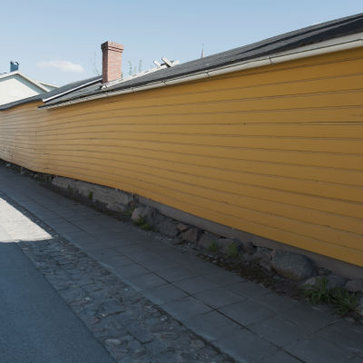 Keltaisen puutalon pitkä lautaseinä Raahessa vanhan kaupungin puutaloalueella