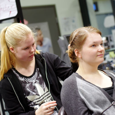 Frisörstuderanden Elin Sigfridsson jobbar på en uppsättning i Wilma Westerlunds hår.