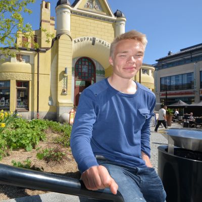 Jalkapalloilija Ilmari Niskanen istuu Kauppahallin edessä.