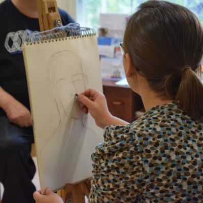 Iana Vulpe piirtää mallina toimivaa Tapani Paleniusta paperille Säynätsalon päiväkeskuksessa.