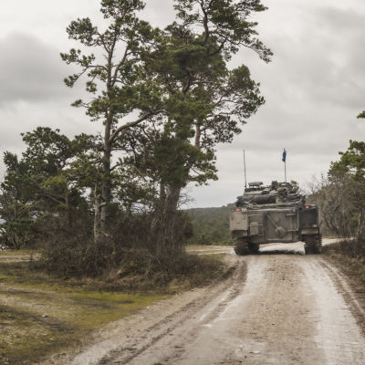 Militärfordon kör på liten sandväg på Gotland.