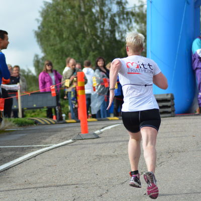 Anna Kultalahti kommer i mål vid Sun City Triathlon i Vasa, tränaren Mika Lehtonen hejar på.