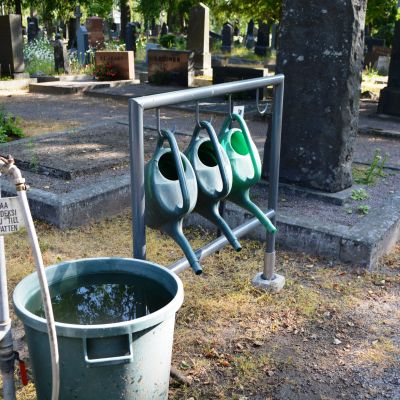 vattenslang och vattenkannor på begravningsplats