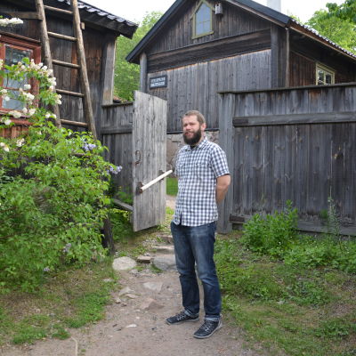 John Björkman står på bakgråden vid ett hus på Klosterbacken.