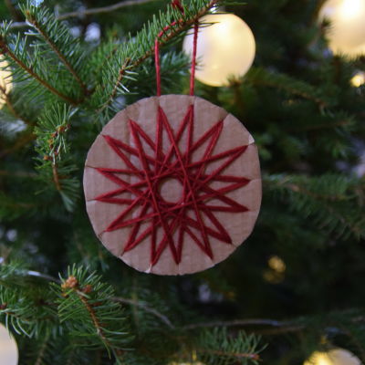 En juldekoration av paff och garn hänger i julgran.