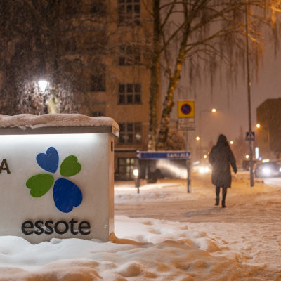 Talvinen maisema Mikkelin keskussairaalan edustalla. Henkilö kävelee kauemmaksi kamerasta lumisateessa. Edustalla kuntayhtymä Essoten kyltti.