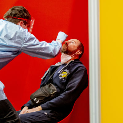 En man testas för coronaviruset av en sjukskötare i skyddsutrustning.