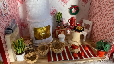 Miniatyrhus med handgjorda saker som kamin, korgar, krukväxter, matta med mera