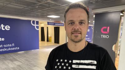 Kimmo Kuosmanen katsoo kameraan, Trion rokotuspiste takana.