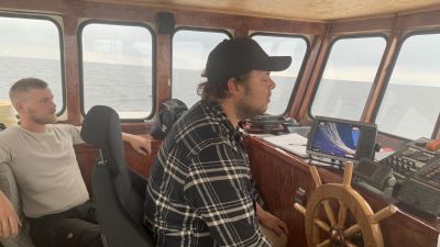 Två män sitter i styrhytten på en fiskbåt