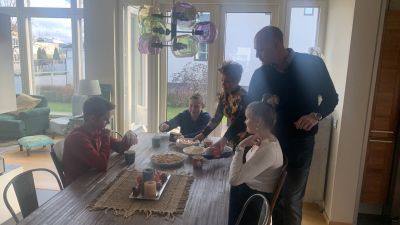 En familj med mamma pappa och tre barn sitter vid ett matbord och äter äppelpaj. 