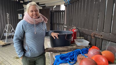Ilse Klockars står vid ett bord med en hink och bojar.