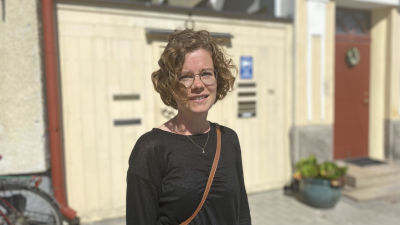 Nea Kronberg, en kvinna med kort och lockigt hår och runda glasögon.